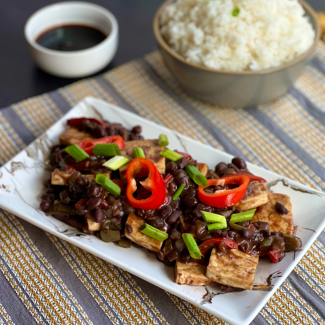 Tofu in Black Bean Sauce; Simple stir-fried Asian inspired dish with minimal ingrediencies full of earthy, fresh flavors. Protein and calcium loaded tofu in a divine sweet and savory black bean sauce, served over a bowl of hot rice.