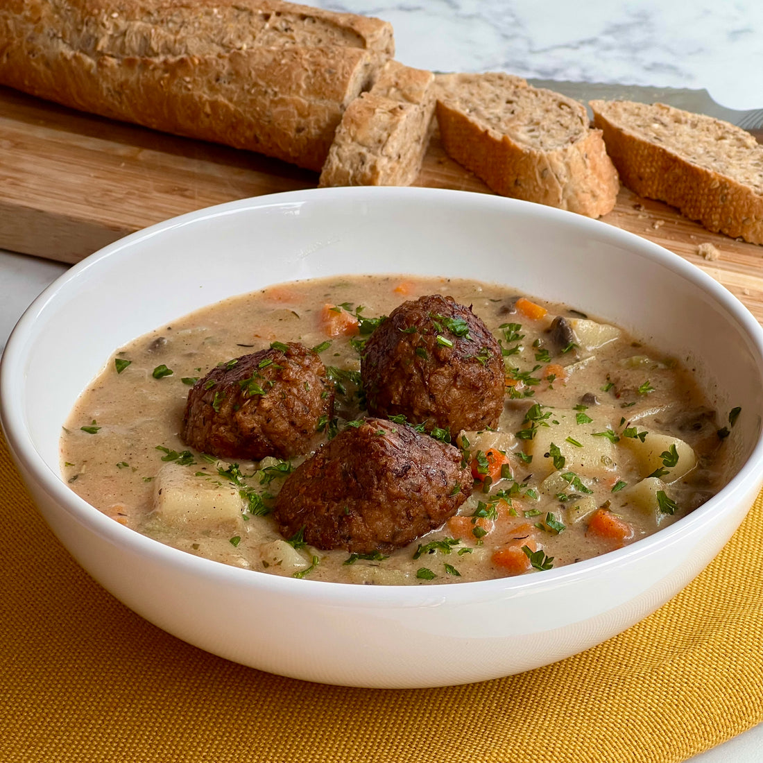 Country Meatball Fricassee; A simple meal filled with comforting flavors of French countryside. Plant based meatballs stewed with healthy vegetables and aromatic garden herbs in a thick, rich creamy sauce. Served with multigrain French crusty bread.